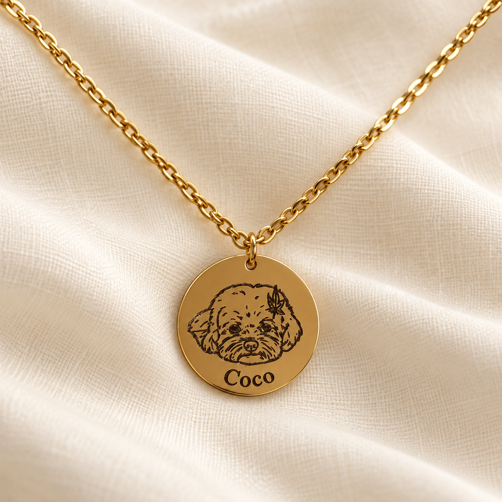 Gold-tone Coco dog portrait necklace on soft ivory linen; styled image